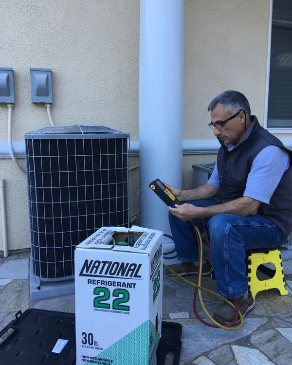 Yagub checking refrigerant on an outdoor AC unit