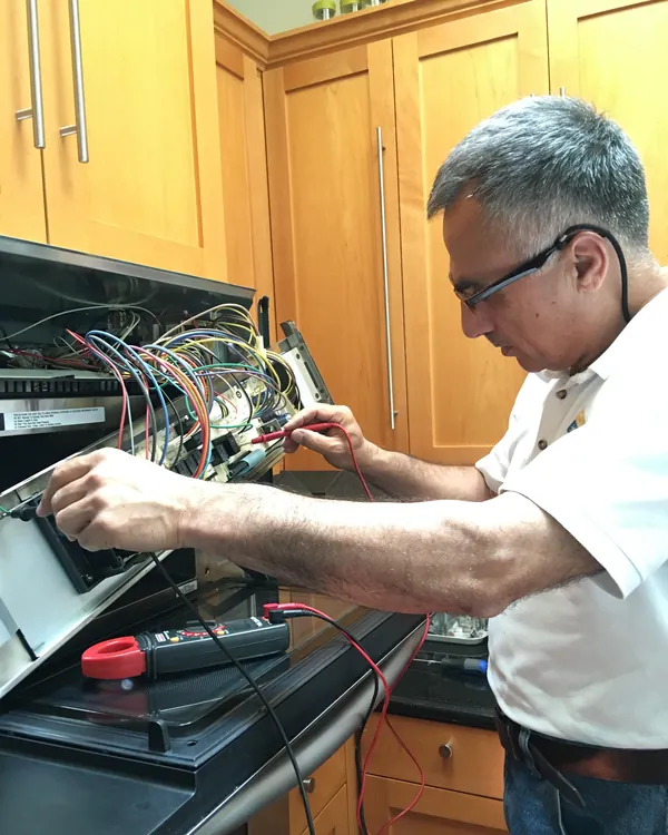 Yagub testing the wiring behind an oven control panel